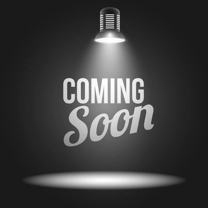 Spotlight shines down on the words 'COMING SOON' against a dark background, signaling an upcoming launch.